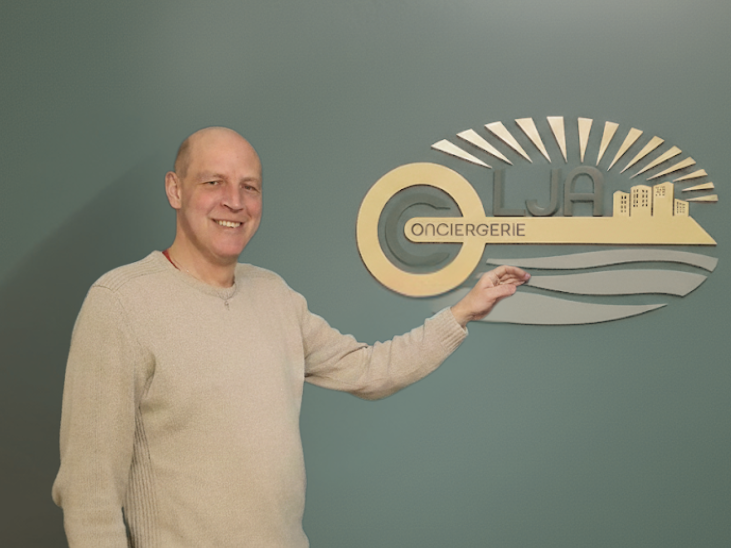 Homme souriant pointeur sur un logo stylisé avec un fond vert.